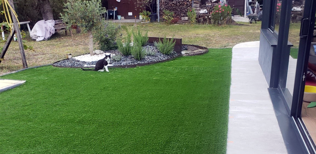 Artificial grass in front of a house with a cat